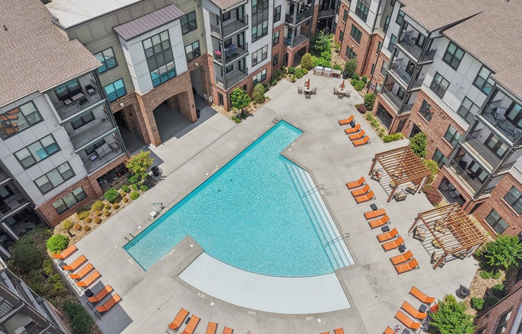 A swimming pool surrounded by orange sun loungers in a courtyard.